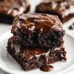Freshly baked fudgy chewy browkies with a rich chocolate brownie base and golden, gooey chocolate chip cookie top, cut into squares on a cooling rack.