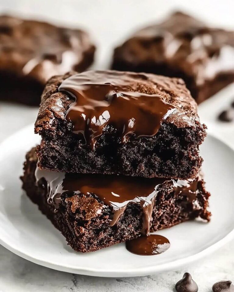 Freshly baked fudgy chewy browkies with a rich chocolate brownie base and golden, gooey chocolate chip cookie top, cut into squares on a cooling rack.