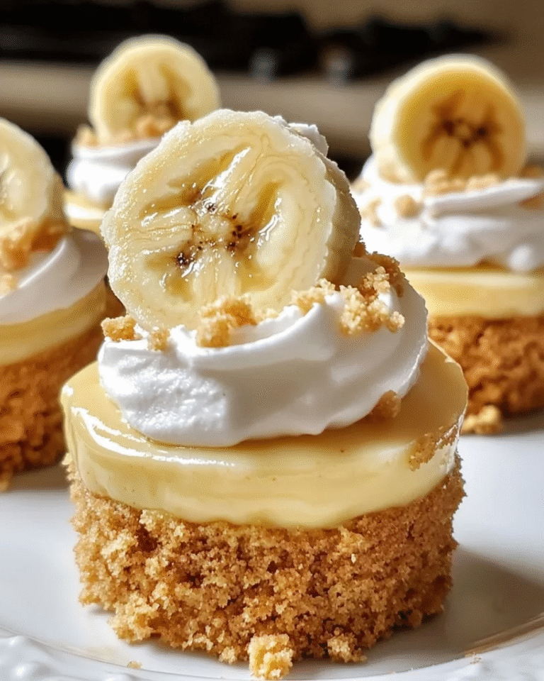 Mini banana pudding cheesecakes topped with whipped cream, fresh banana slices, and vanilla wafers on a white serving platter.